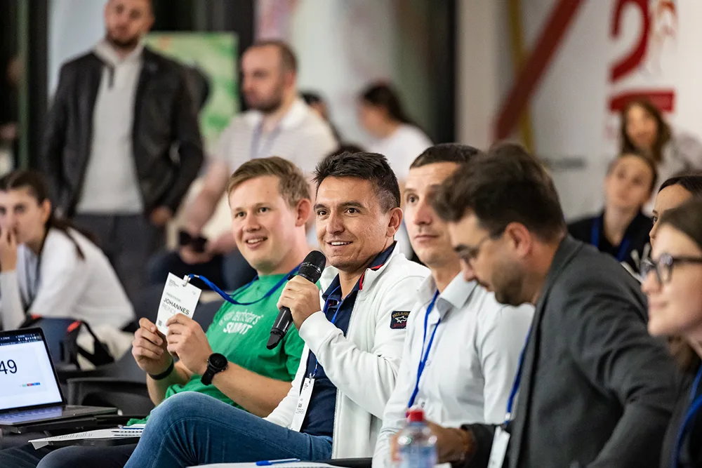 The judging panel smiling as one of them answers a team into a microphone