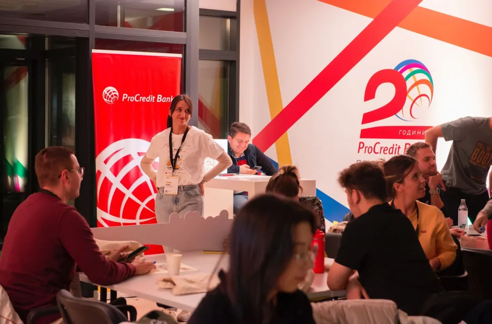 An organiser smiling at the teams beside the partner's banner