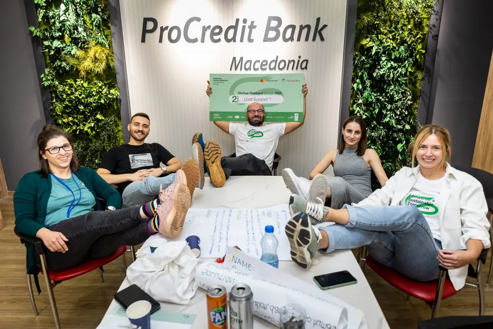 The second-place team with their feet on the table, one of them holding up the cheque