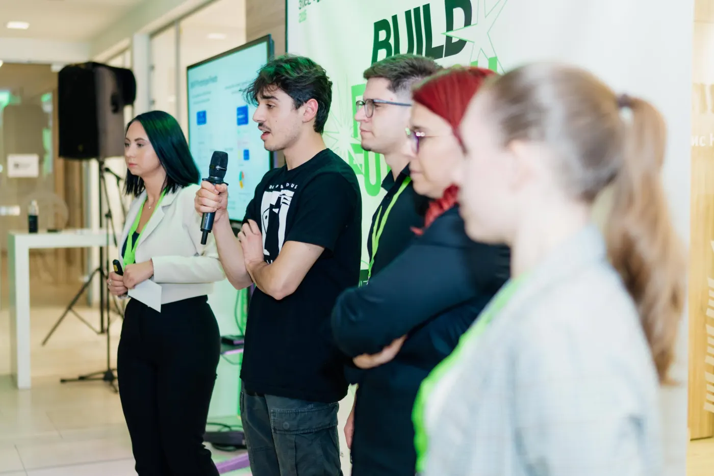 A team presenting their idea on stage with the Build Fintech backdrop behind them