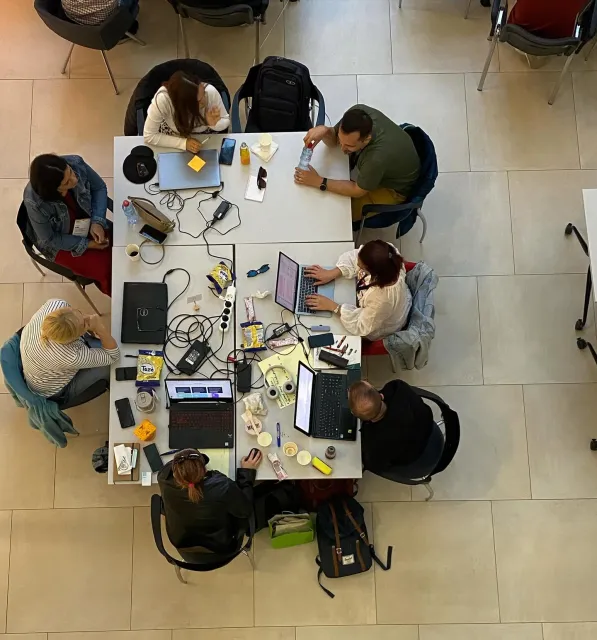 A team around a table of laptops and cables, seen from above